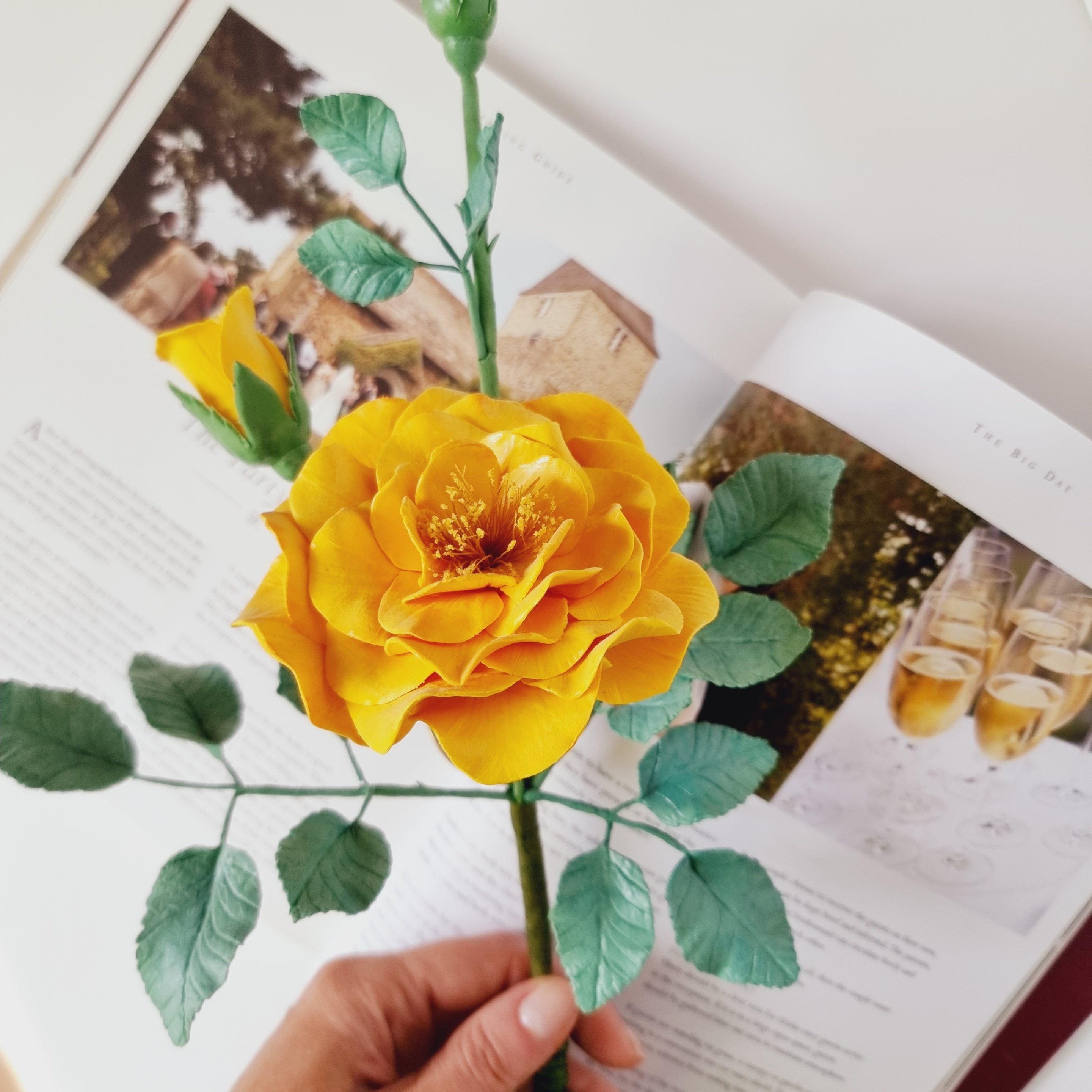 Elegant handmade clay garden rose in a glass holder, a timeless decorative piece.