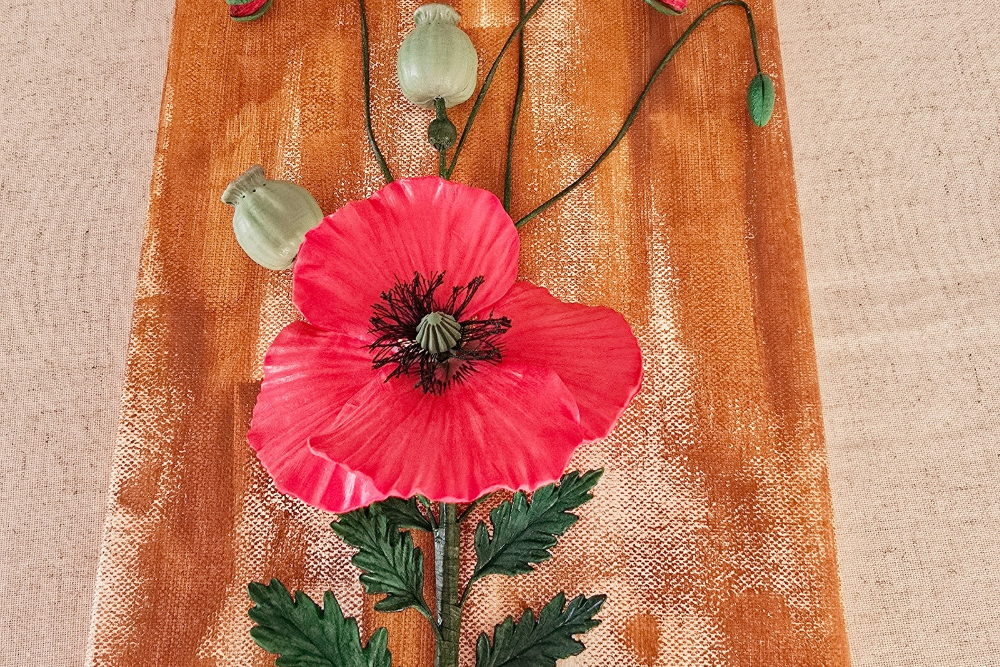 Elegant clay poppy artwork hanging on a white wall with gold accents, adding a modern touch to the space.